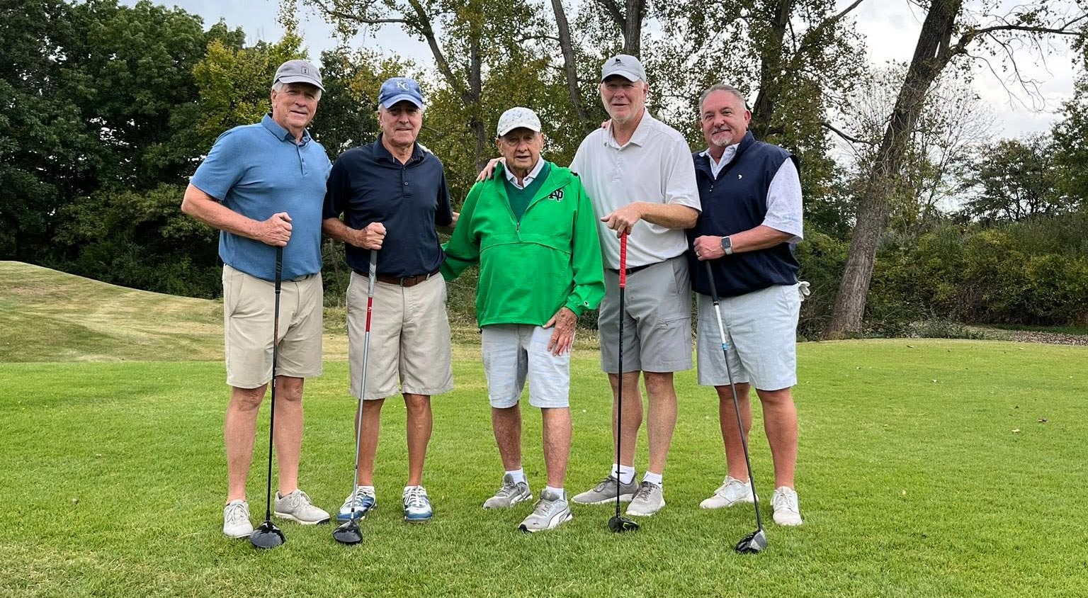 5 men standing on golf course facing the camera